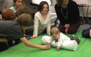 Baby plays with ball that a student hands to him.